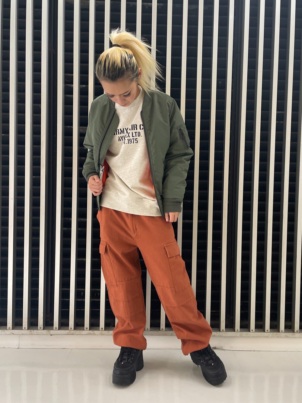 グリーン系のMA-1、レッド系のカーゴパンツ、ベージュ系のスウェットを着用したレディースの冬コーディネートの2枚目の写真