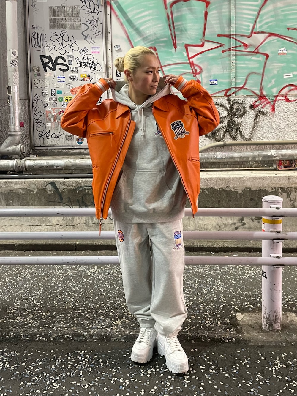パープル系のスウェットパンツ、オレンジ系のジャケット/アウターを着用したレディースの冬コーディネートの2枚目の写真
