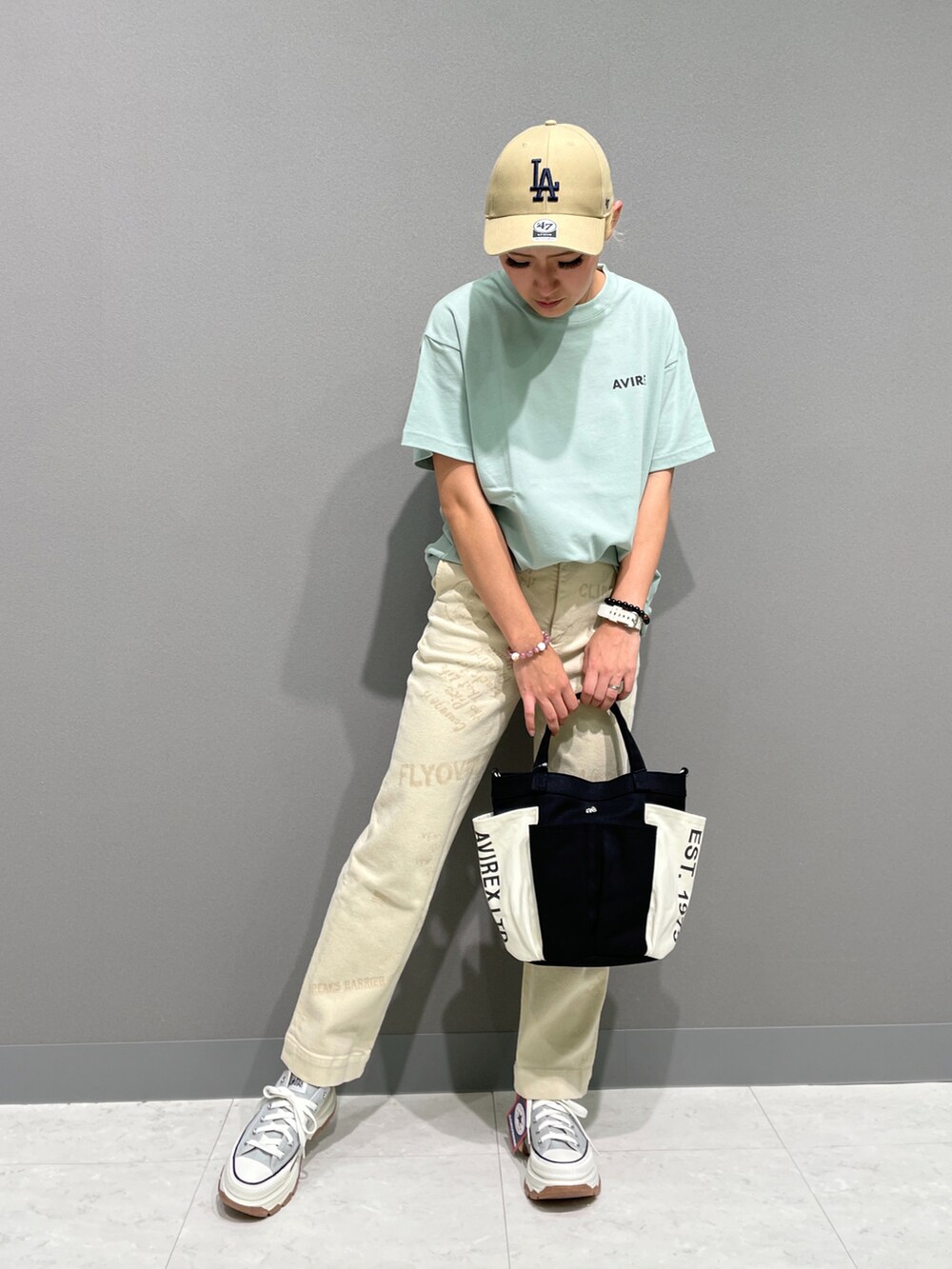 グリーン系のTシャツ/カットソー、ホワイト系のチノパンツ、ブラック系のトートバッグを着用したレディースの夏コーディネートの2枚目の写真