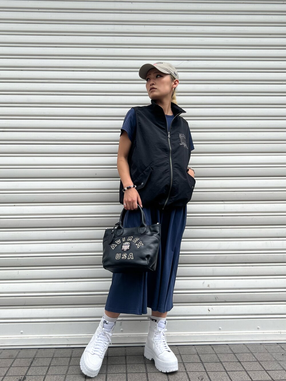 ブラック系のベスト、ピンク系のワンピース、ベージュ系の帽子を着用したレディースの夏コーディネートの2枚目の写真