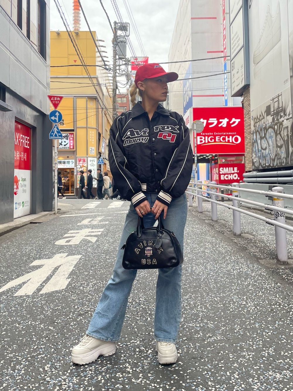 ブルー系のデニムパンツ、ブラック系のボストンバッグ、ブラック系のブルゾンを着用したレディースの秋コーディネートの2枚目の写真