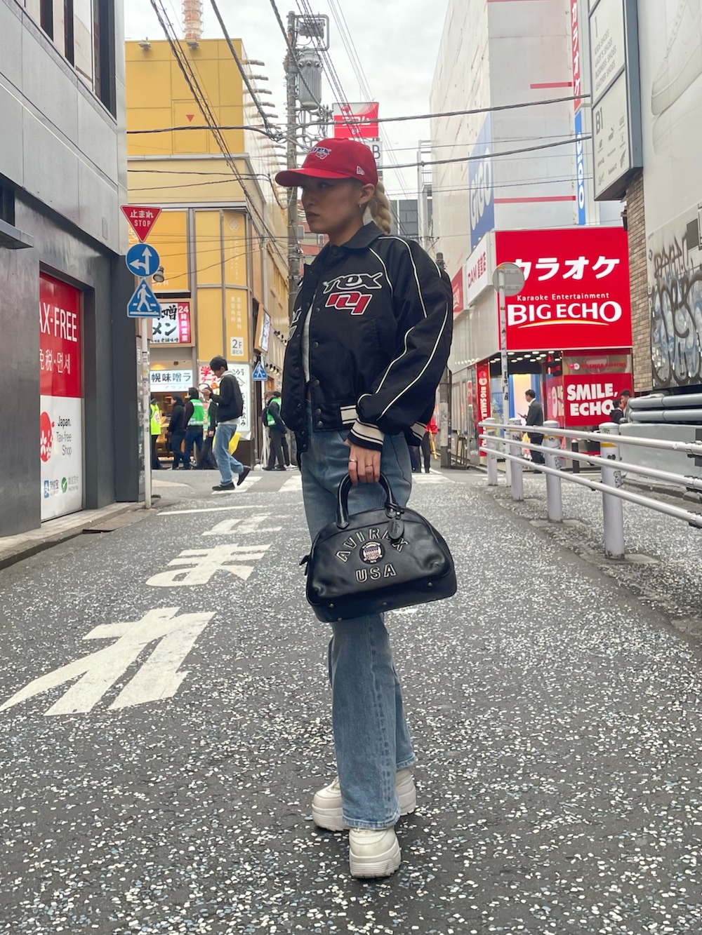 ブルー系のデニムパンツ、ブラック系のボストンバッグ、ブラック系のブルゾンを着用したレディースの秋コーディネートの4枚目の写真