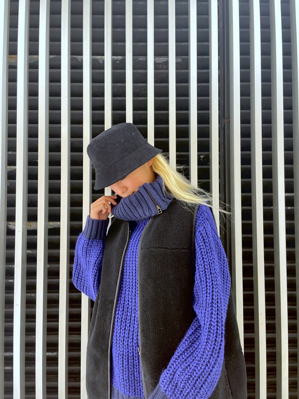 ブルー系のニット/セーター、グレー系のスカート、ブラック系のベストを着用したレディースの秋コーディネートの2枚目の写真