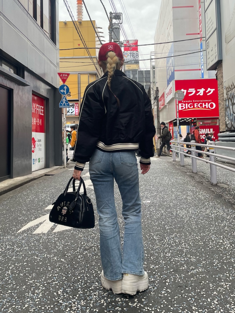 ブルー系のデニムパンツ、ブラック系のボストンバッグ、ブラック系のブルゾンを着用したレディースの秋コーディネートの3枚目の写真