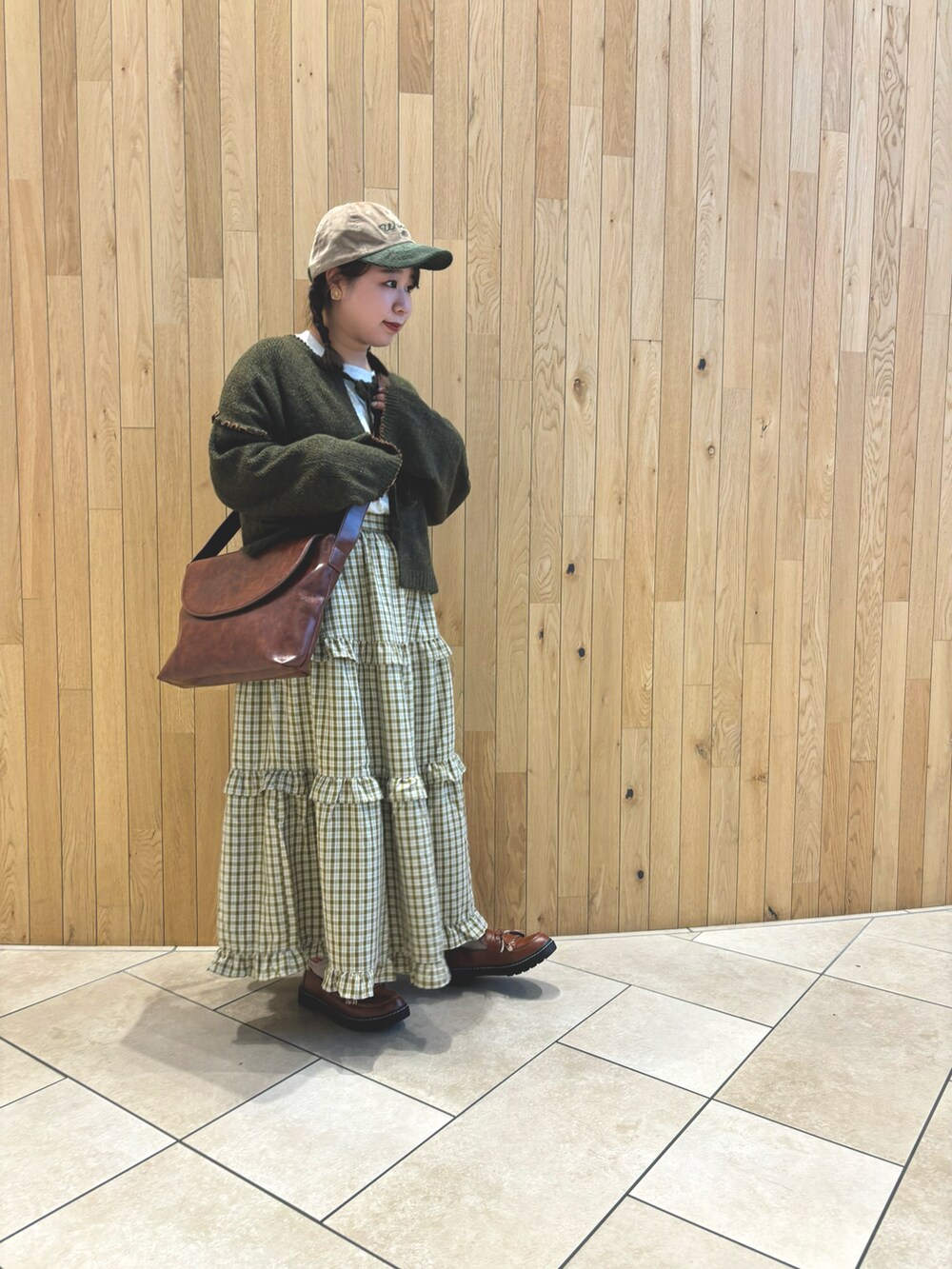 グリーン系のスカート、グリーン系のカーディガン/ボレロ、ブラウン系のハンドバッグを着用したレディースの秋コーディネートの2枚目の写真