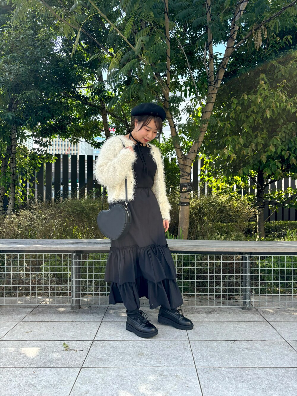 ブラック系のスカート、ブラック系のブーツ、ブラック系のハンドバッグを着用したレディースの秋コーディネートの2枚目の写真