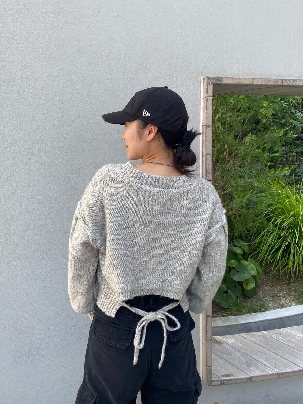 グレー系のニット/セーター、ブラック系のデニムパンツ、ブラック系のショルダーバッグを着用したレディースの秋コーディネートの2枚目の写真