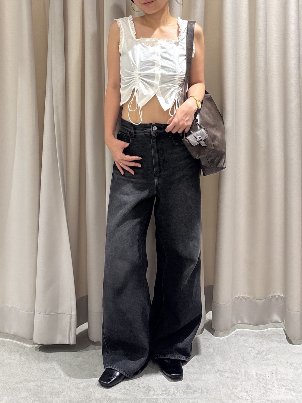 ホワイト系のトップス、ブラック系のデニムパンツ、ブラウン系のショルダーバッグを着用したレディースの夏コーディネートの2枚目の写真
