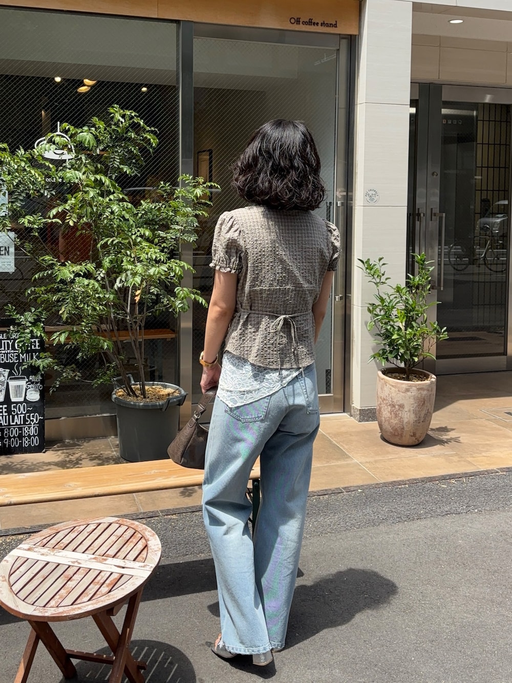 ベージュ系のシャツ/ブラウス、ブルー系のデニムパンツ、ブラウン系のショルダーバッグを着用したレディースの夏コーディネートの2枚目の写真