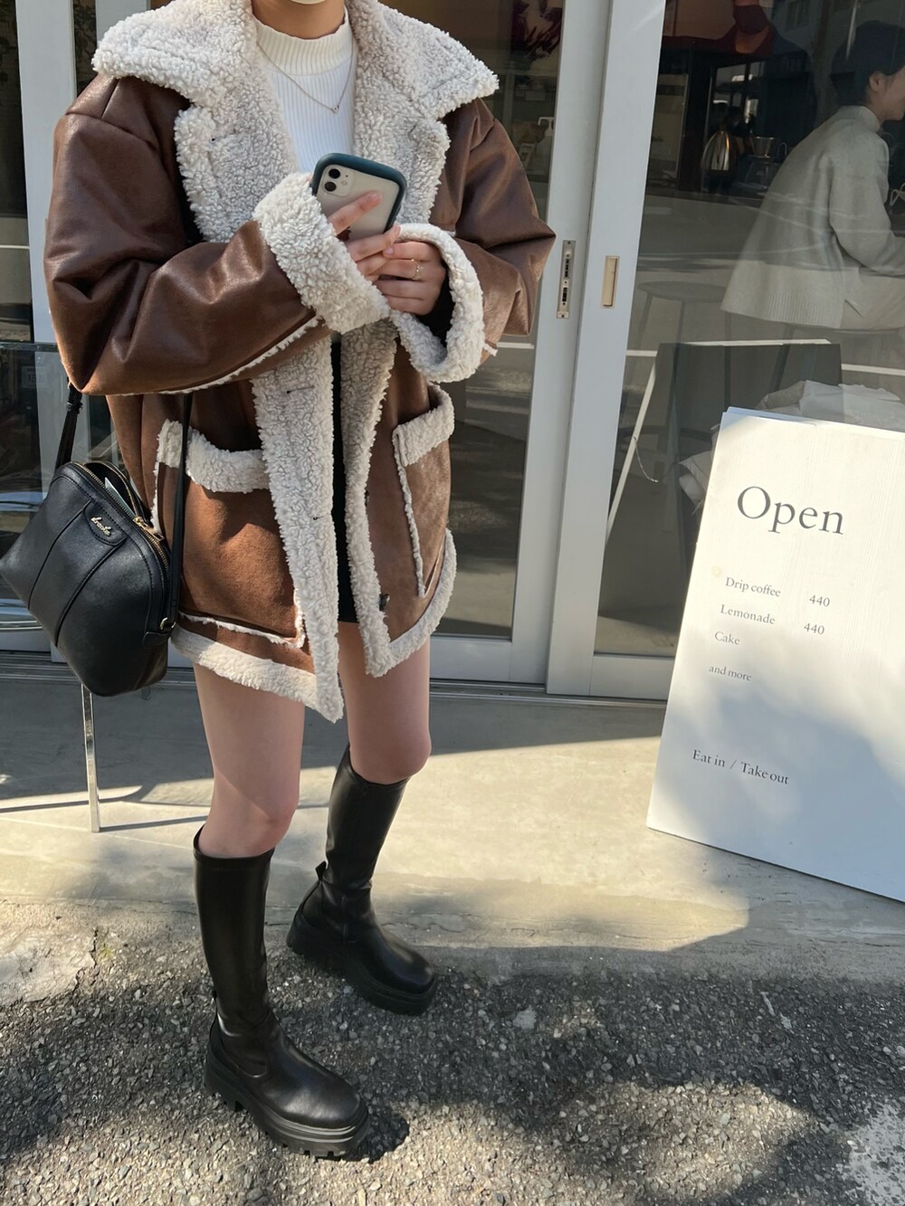 ブラウン系のムートンコート、ブラック系のブーツ、ブラック系のその他パンツを着用したレディースの冬コーディネートの3枚目の写真