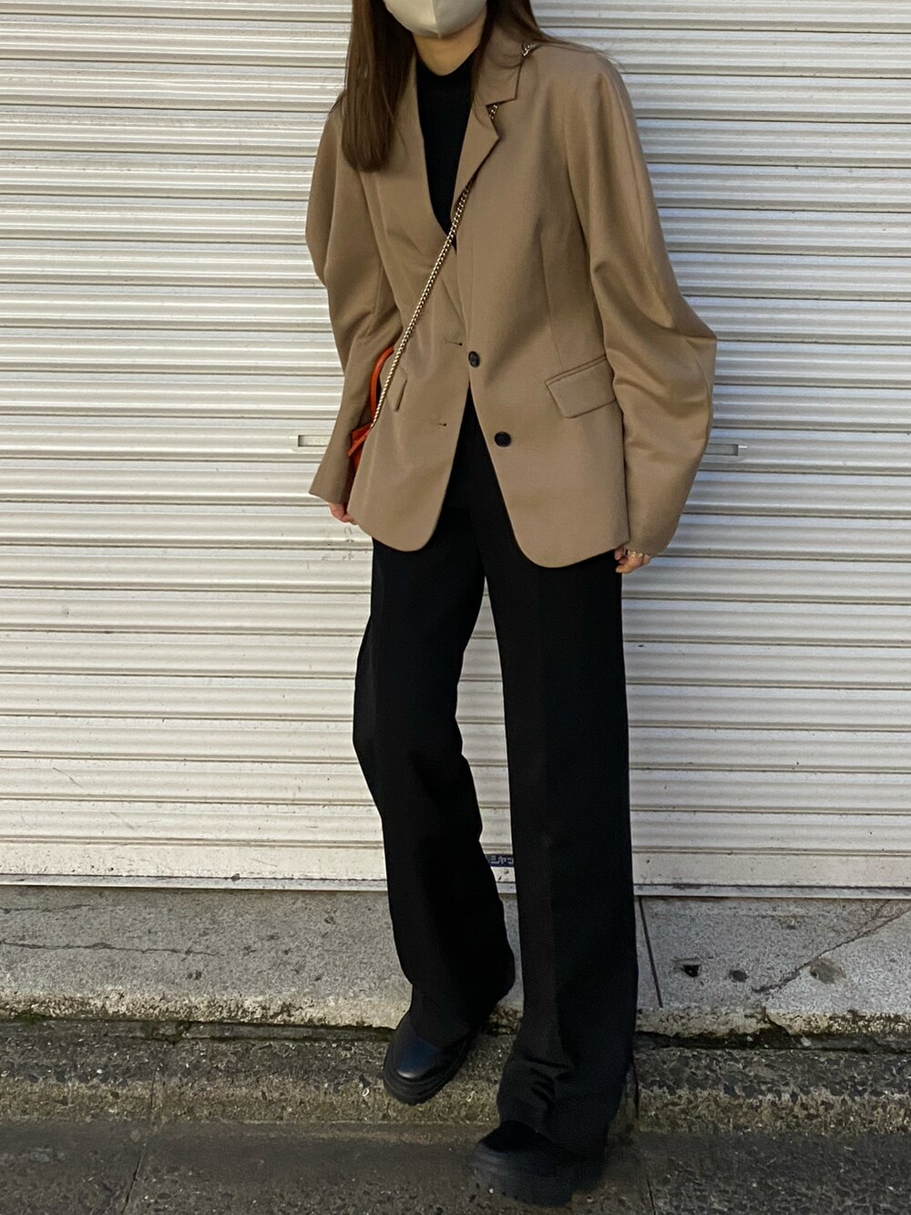 ベージュ系のテーラードジャケット、オレンジ系のショルダーバッグ、ブラック系のスラックスを着用したレディースの春コーディネートの2枚目の写真