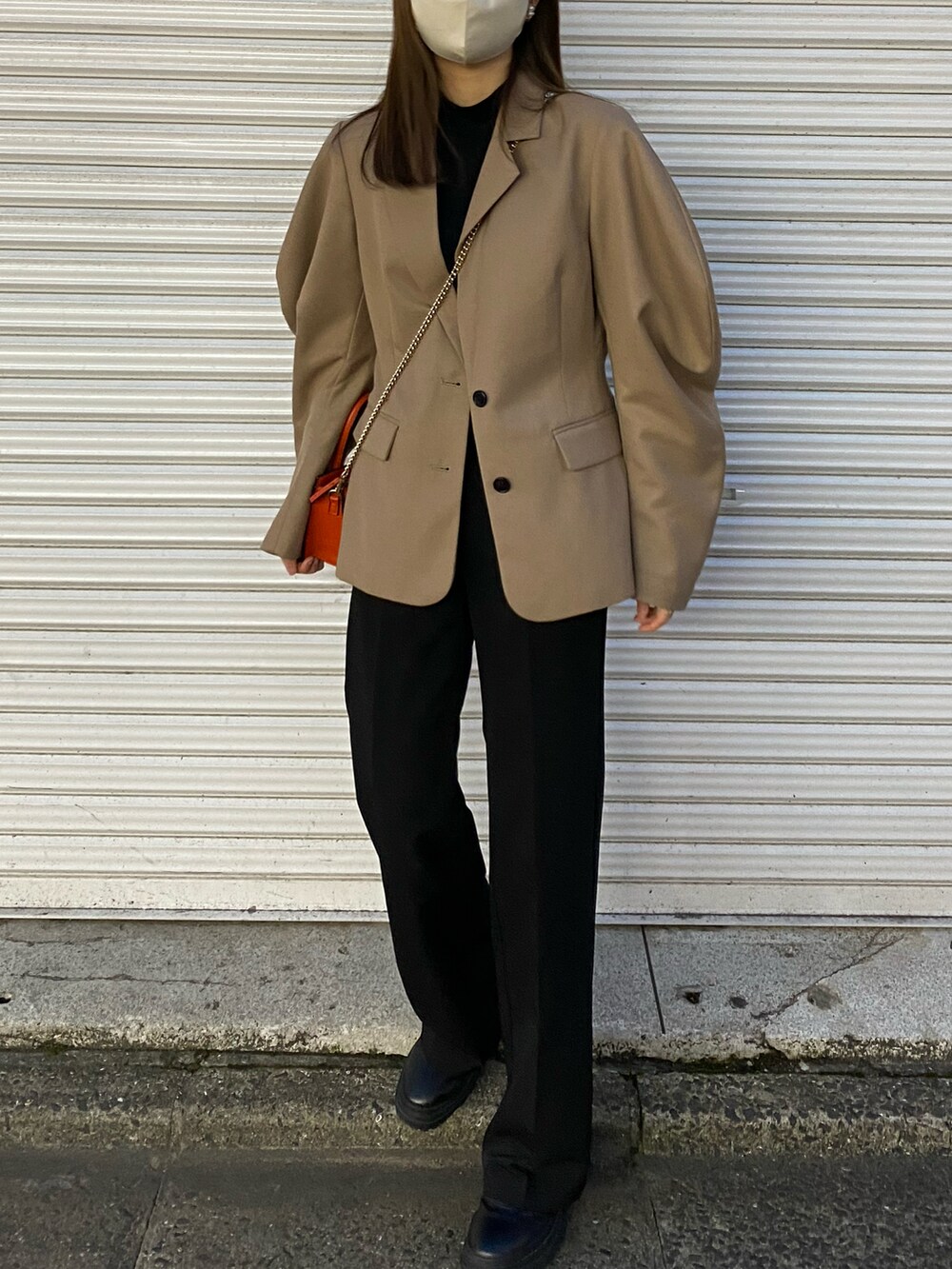 ベージュ系のテーラードジャケット、オレンジ系のショルダーバッグ、ブラック系のスラックスを着用したレディースの春コーディネートの3枚目の写真