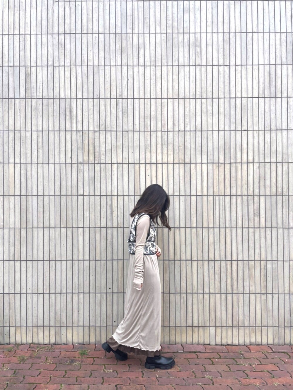 ブラック系のブーツ、ベージュ系のトップス、その他のベストを着用したレディースの秋コーディネートの2枚目の写真