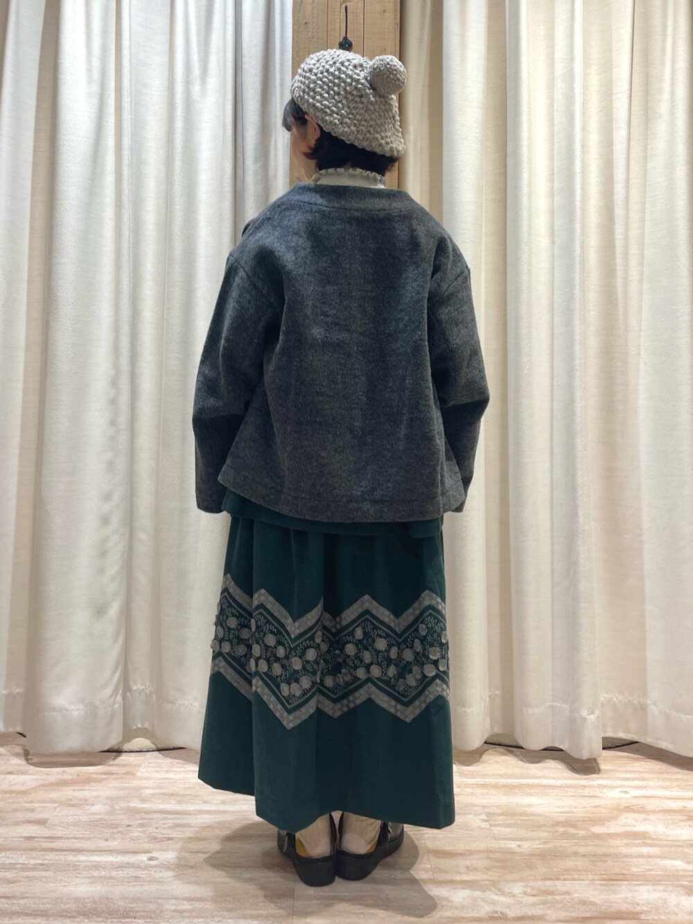 グリーン系のシャツ/ブラウス、グレー系のニット/セーター、グリーン系のスカートを着用したレディースの冬コーディネートの3枚目の写真