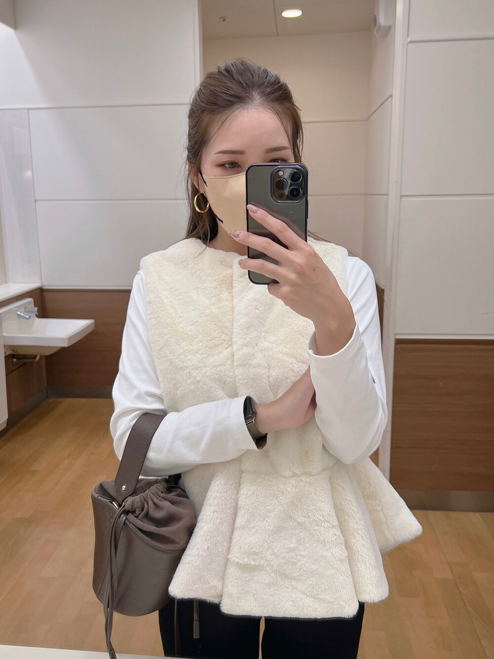 ホワイト系のベスト、ブラック系のその他パンツ、ベージュ系のスニーカーを着用したレディースの秋コーディネートの2枚目の写真