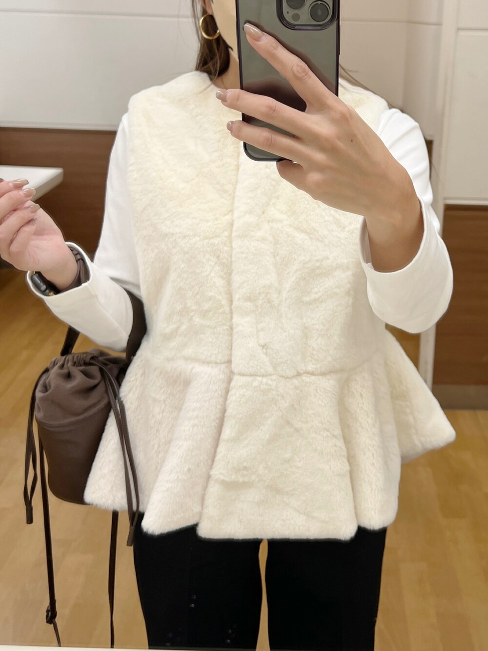 ホワイト系のベスト、ブラック系のその他パンツ、ベージュ系のスニーカーを着用したレディースの秋コーディネートの3枚目の写真