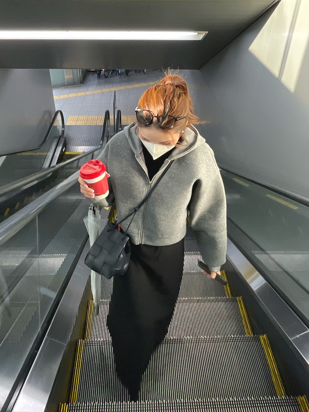 グレー系のパーカー、ブラック系のワンピース、ブルー系のショルダーバッグを着用したレディースの冬コーディネートの3枚目の写真