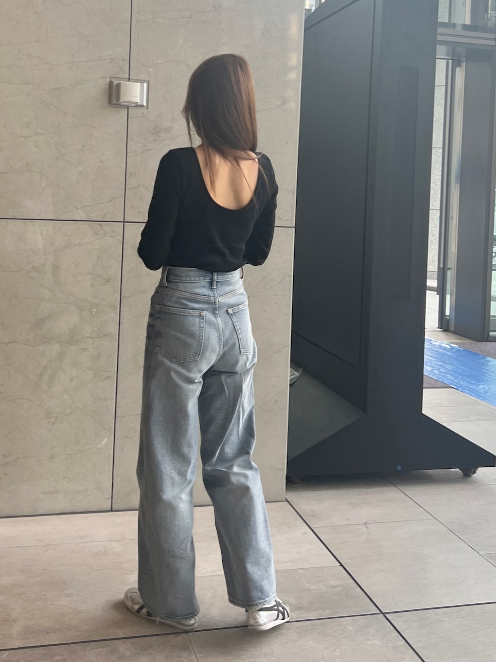 ブラック系のTシャツ/カットソー、ブルー系のデニムパンツを着用したレディースの春コーディネートの3枚目の写真