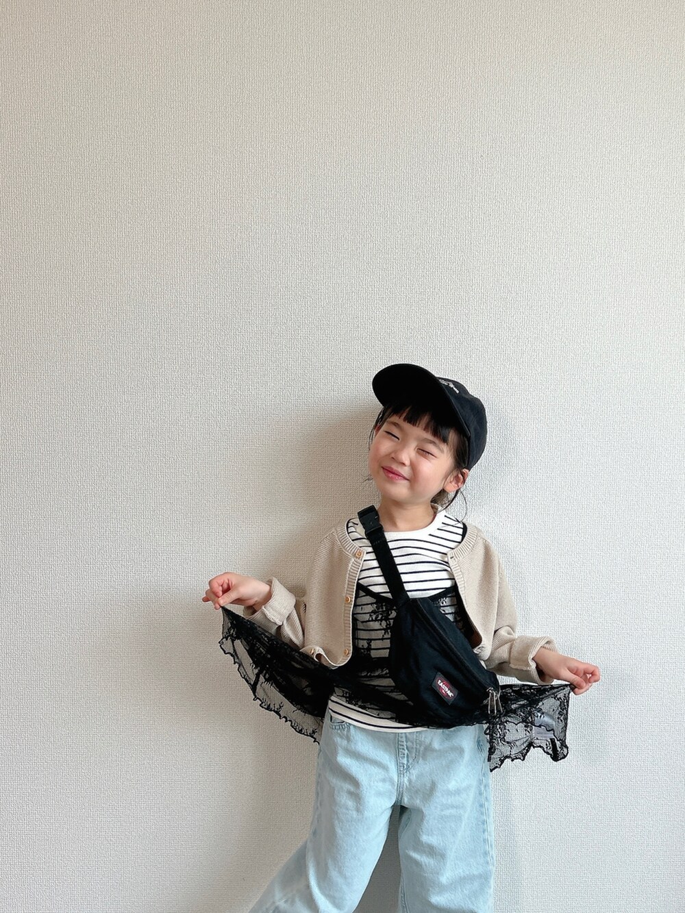 ホワイト系のTシャツ/カットソー、ベージュ系のカーディガン/ボレロ、ブラック系のワンピース/ドレスを着用したキッズの春コーディネートの2枚目の写真