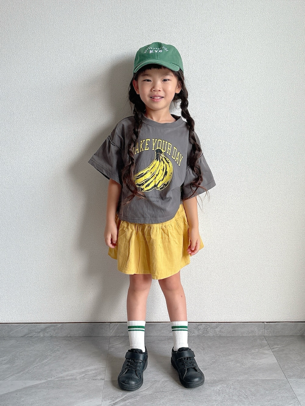 ブラック系のスニーカー、グレー系のTシャツ/カットソー、イエロー系のスカートを着用したキッズの夏コーディネートの4枚目の写真