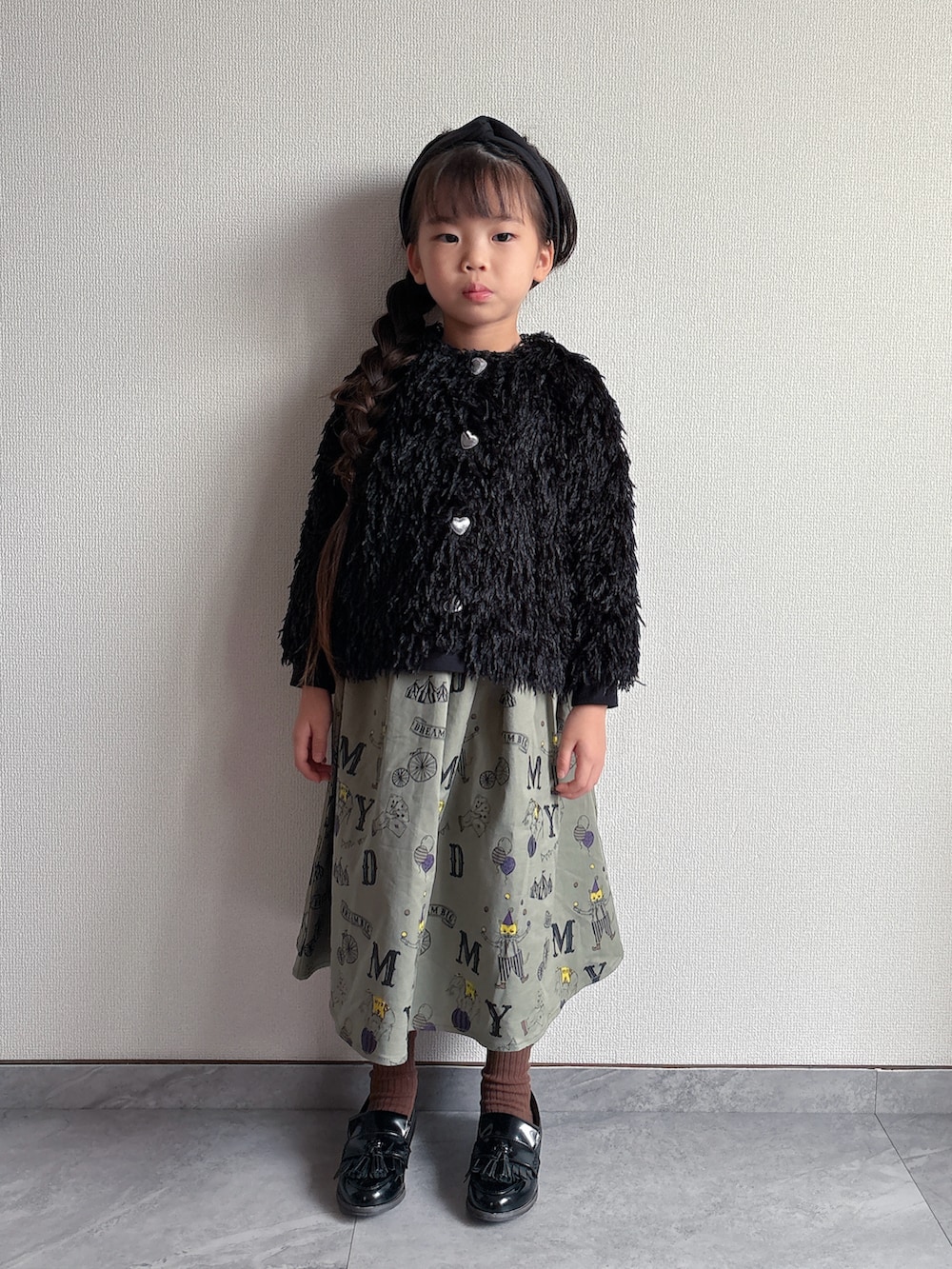 ブラック系のカーディガン/ボレロ、グリーン系のスカートを着用したキッズの秋コーディネートの3枚目の写真
