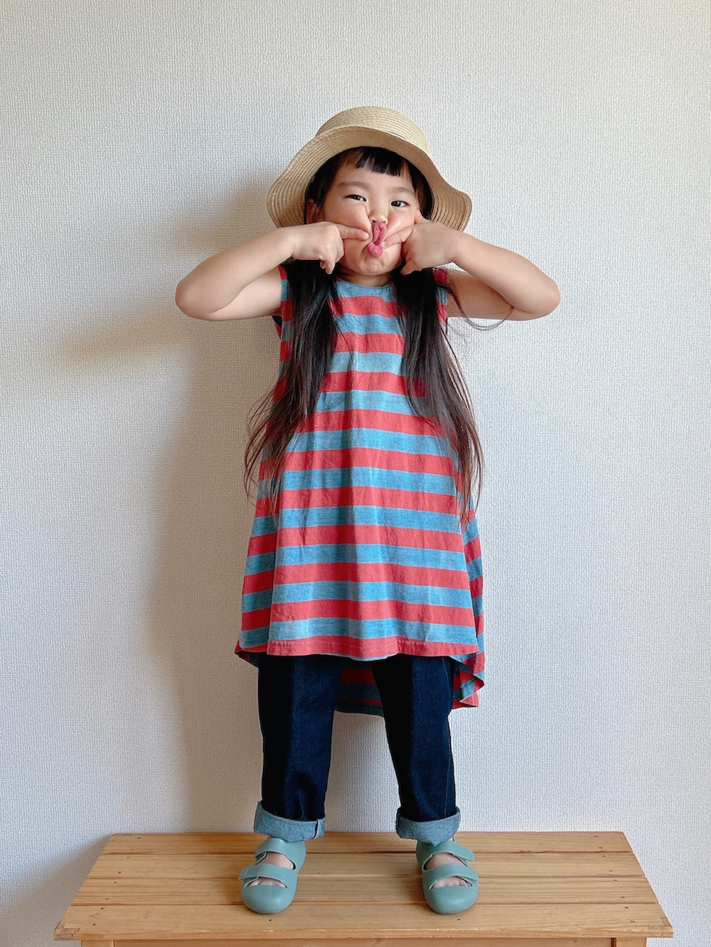 レッド系のワンピース、ベージュ系のデニムパンツ、グリーン系のサンダルを着用したキッズの夏コーディネートの4枚目の写真