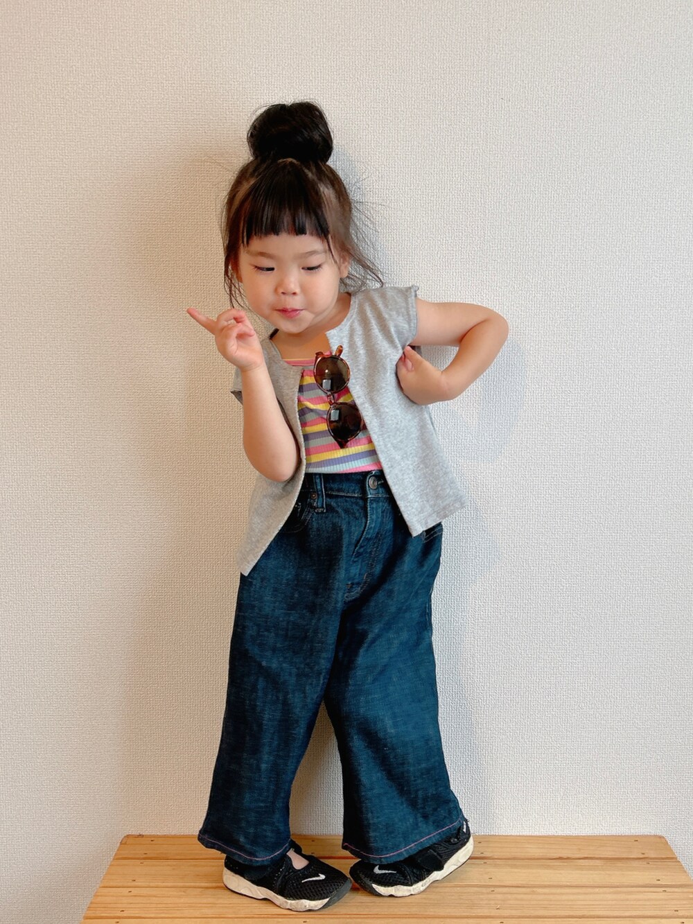 イエロー系のキャミソール、グレー系のベスト、ブルー系のデニムパンツを着用したキッズの夏コーディネートの2枚目の写真