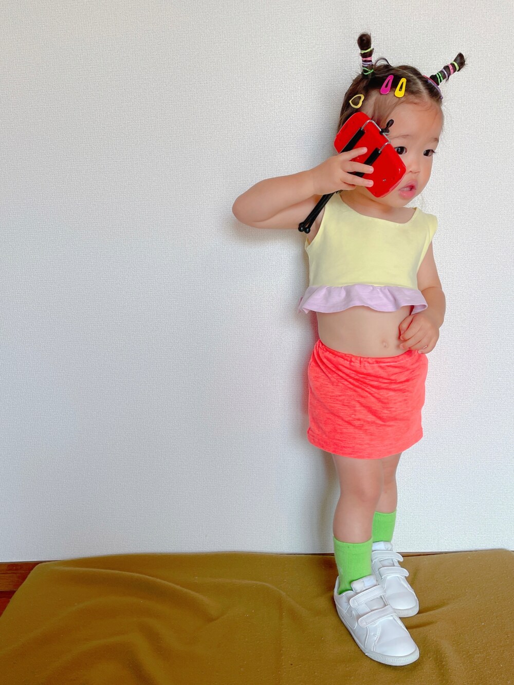 ピンク系のスカート、ホワイト系のスニーカー、イエロー系のスポーツブラを着用したキッズの秋コーディネートの3枚目の写真