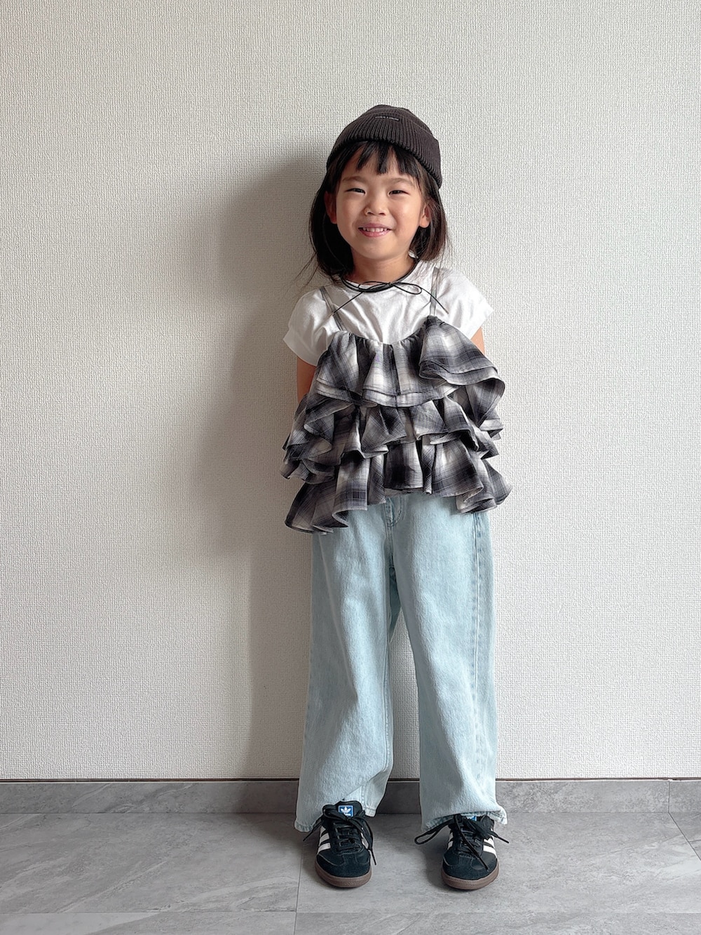 ブラック系のキャミソール、ブルー系のデニムパンツ、ブラック系のスニーカーを着用したキッズの夏コーディネートの2枚目の写真