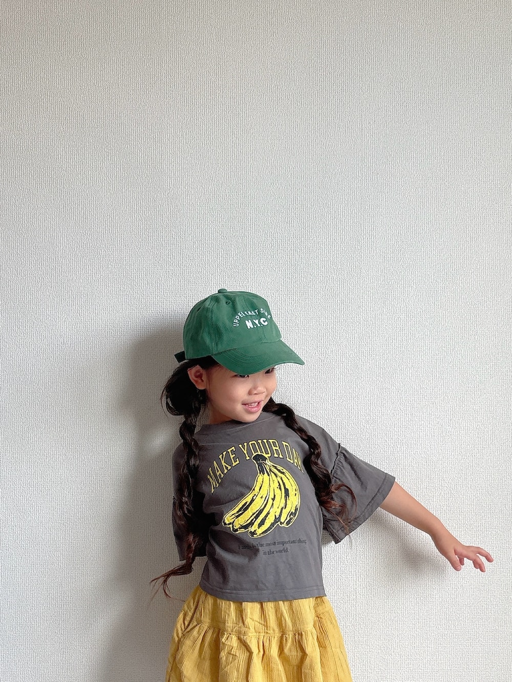 ブラック系のスニーカー、グレー系のTシャツ/カットソー、イエロー系のスカートを着用したキッズの夏コーディネートの3枚目の写真