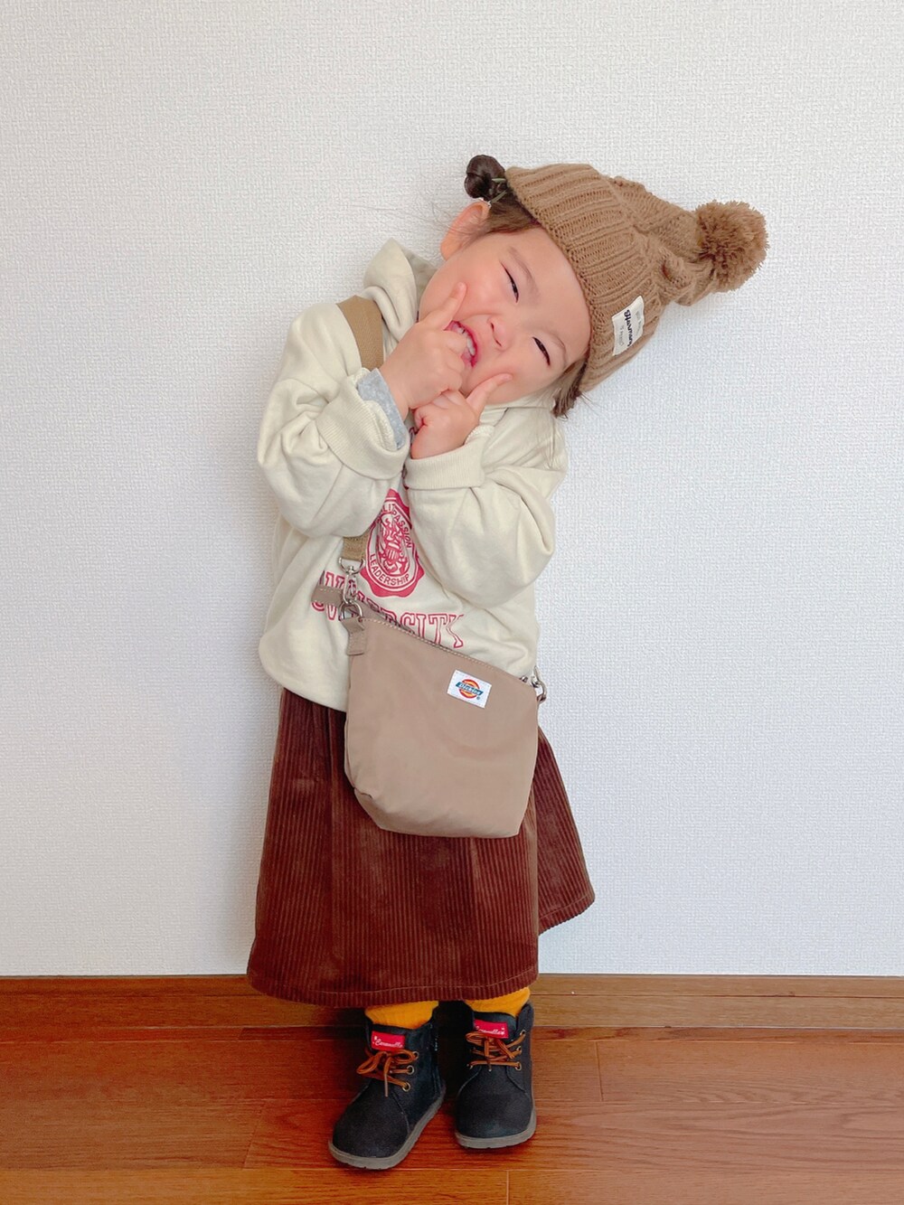 ホワイト系のスウェット、ベージュ系のショルダーバッグ、ブラウン系のスカートを着用したキッズの冬コーディネートの2枚目の写真