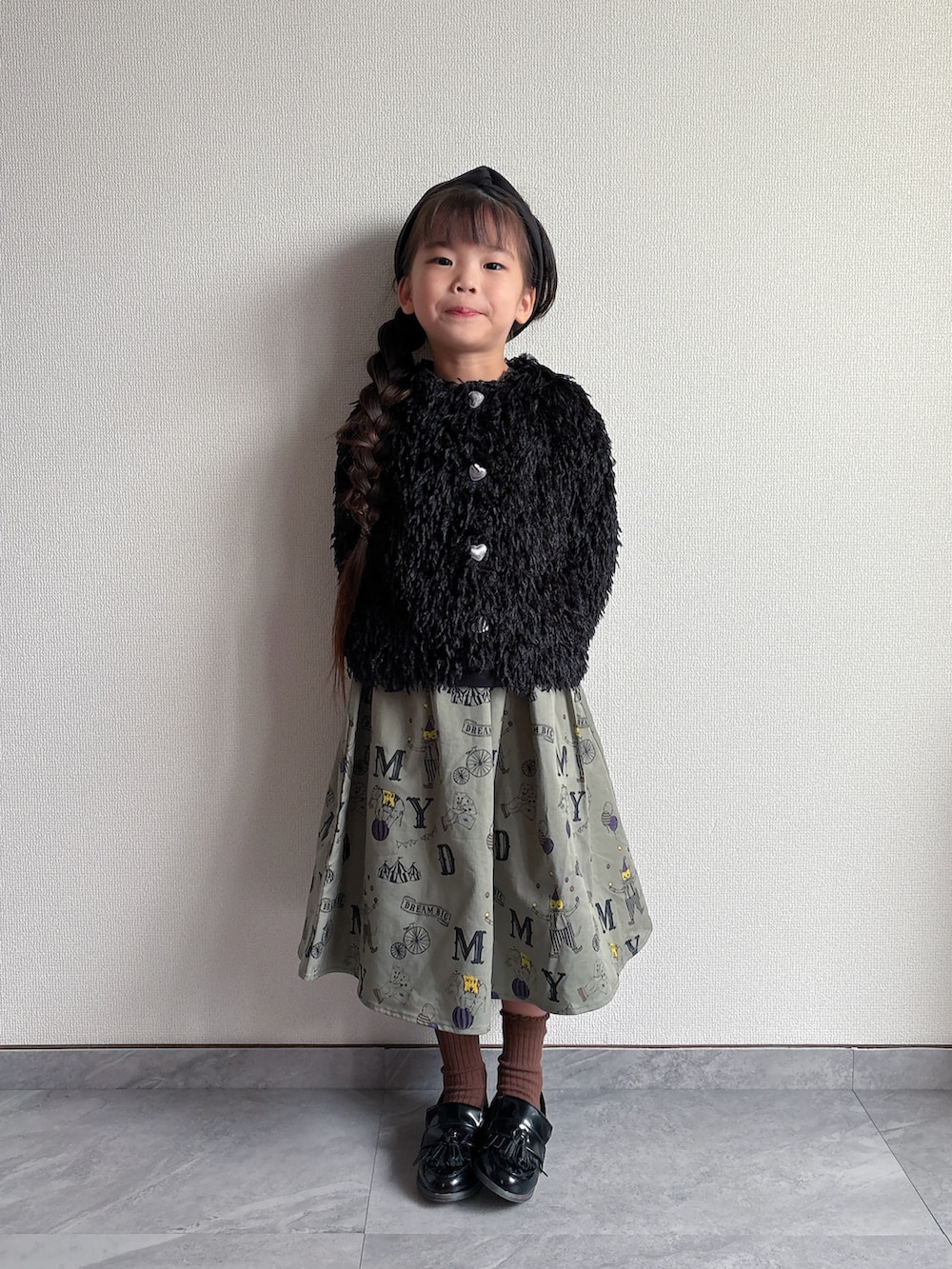 ブラック系のカーディガン/ボレロ、グリーン系のスカートを着用したキッズの秋コーディネートの5枚目の写真
