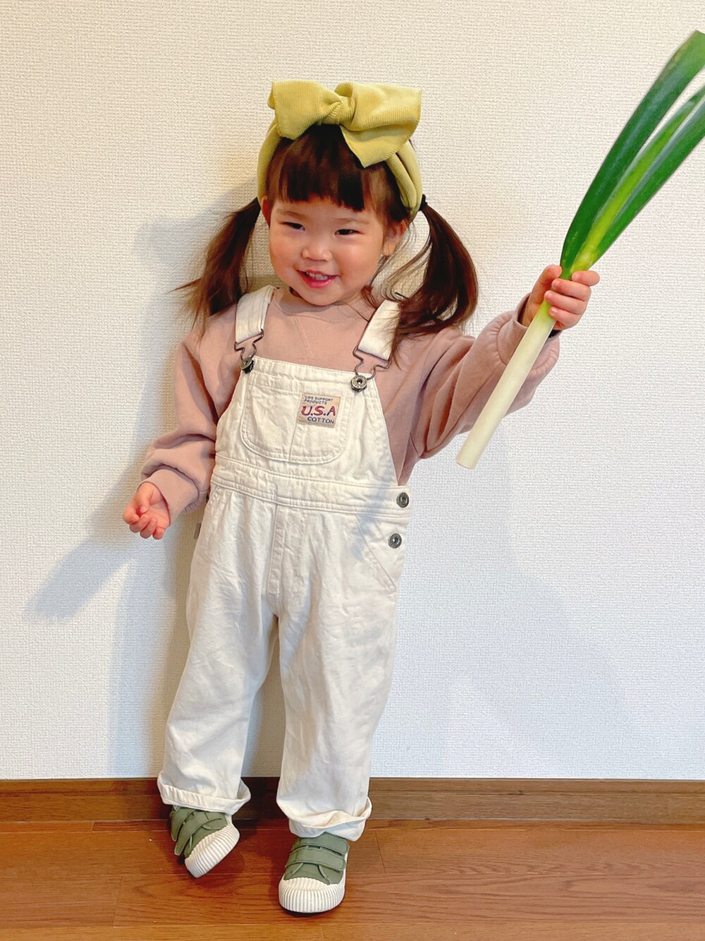 ピンク系のスウェット、ホワイト系のサロペット/オーバーオール、グリーン系のスニーカーを着用したキッズの冬コーディネートの3枚目の写真