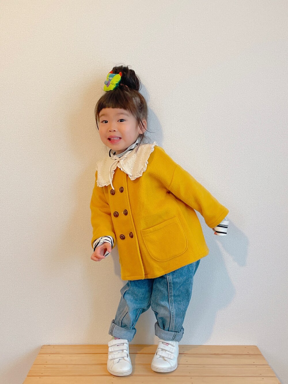 イエロー系のノーカラーコート、ブルー系のデニムパンツ、ホワイト系のスニーカーを着用したキッズの冬コーディネートの4枚目の写真