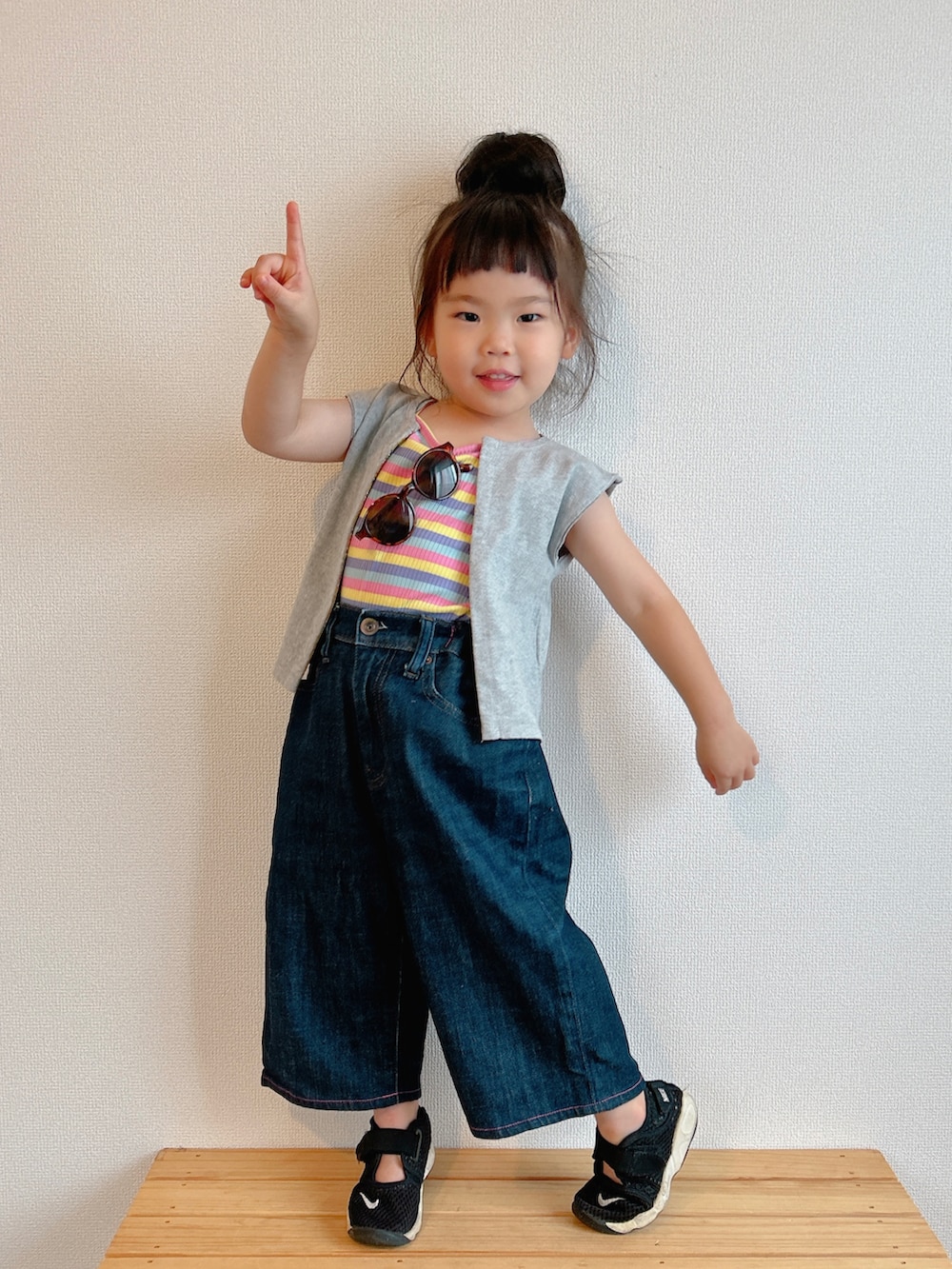 イエロー系のキャミソール、グレー系のベスト、ブルー系のデニムパンツを着用したキッズの夏コーディネートの4枚目の写真