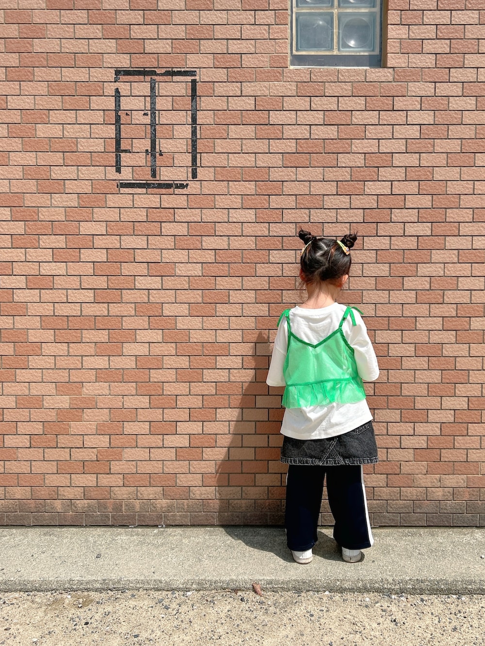 グリーン系のキャミソール、ホワイト系のTシャツ/カットソー、ブラック系のデニムスカートを着用したキッズの春コーディネートの3枚目の写真