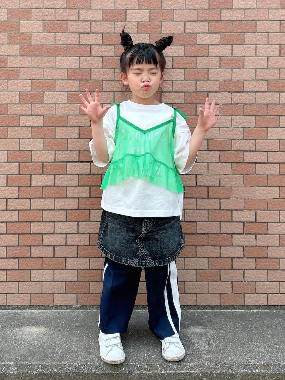 グリーン系のキャミソール、ホワイト系のTシャツ/カットソー、ブラック系のデニムスカートを着用したキッズの春コーディネートの4枚目の写真