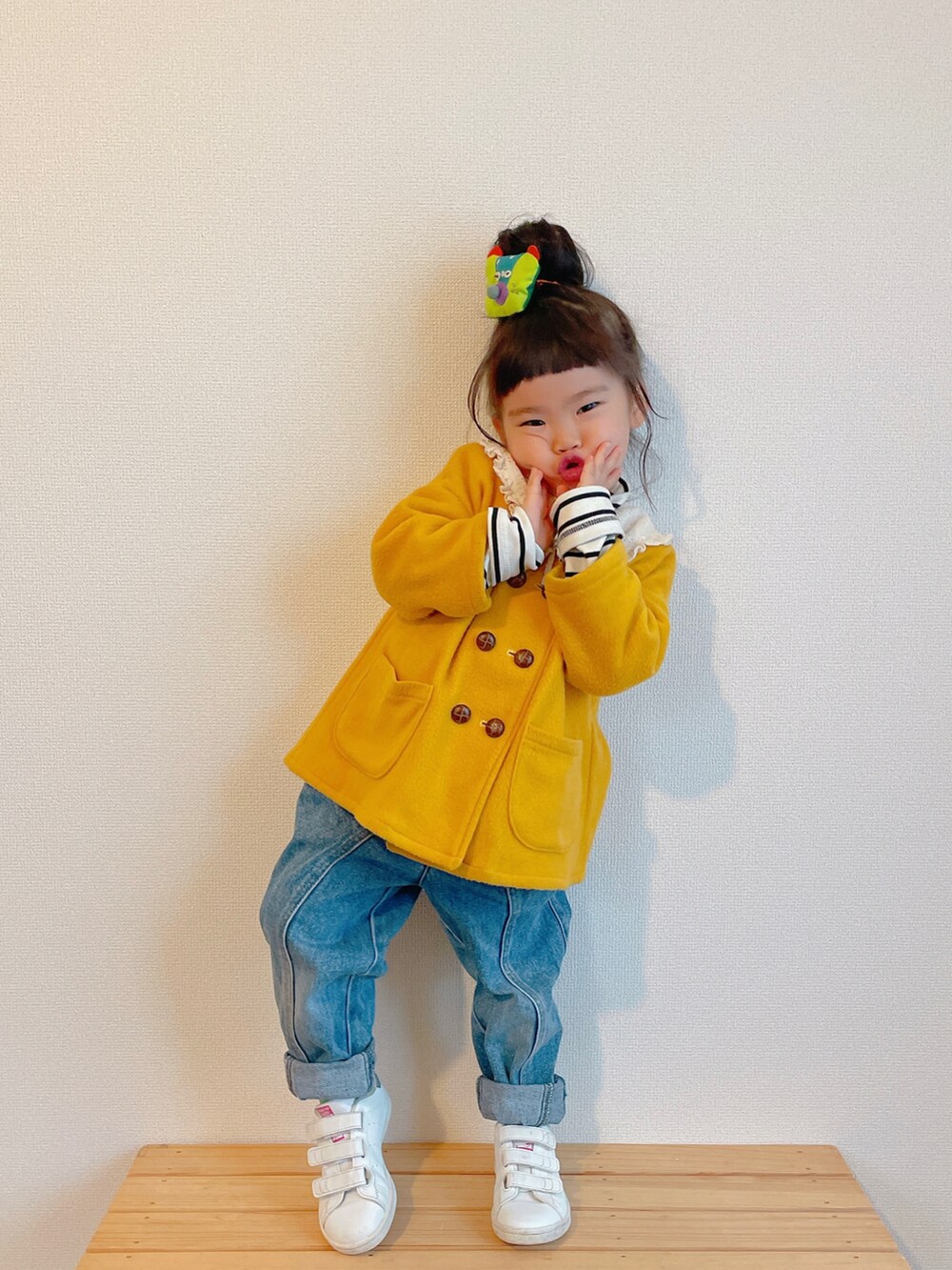 イエロー系のノーカラーコート、ブルー系のデニムパンツ、ホワイト系のスニーカーを着用したキッズの冬コーディネートの3枚目の写真