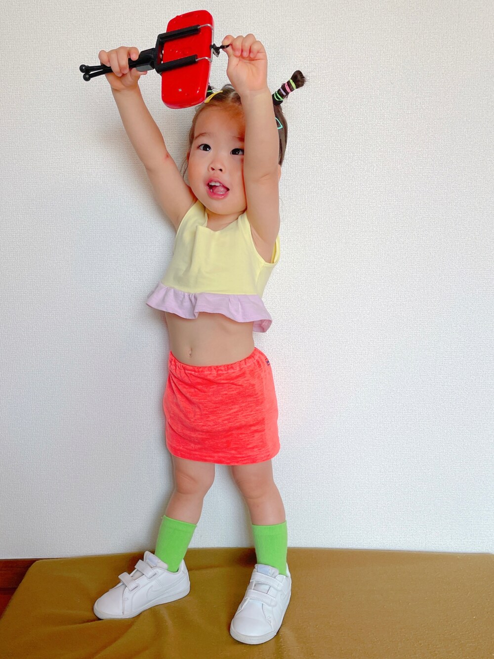 ピンク系のスカート、ホワイト系のスニーカー、イエロー系のスポーツブラを着用したキッズの秋コーディネートの4枚目の写真
