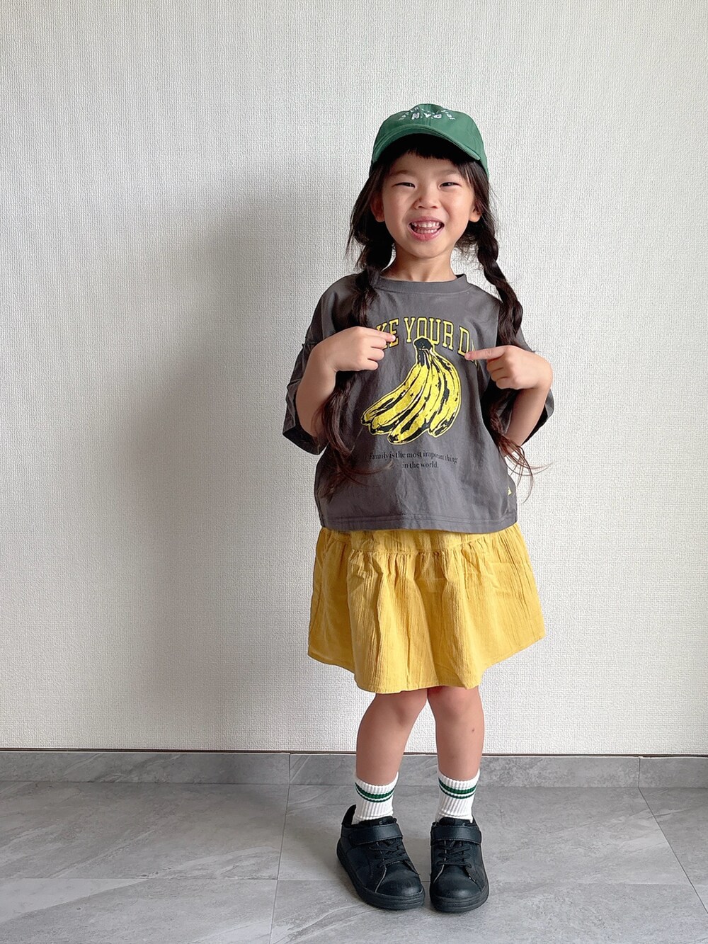 ブラック系のスニーカー、グレー系のTシャツ/カットソー、イエロー系のスカートを着用したキッズの夏コーディネートの5枚目の写真