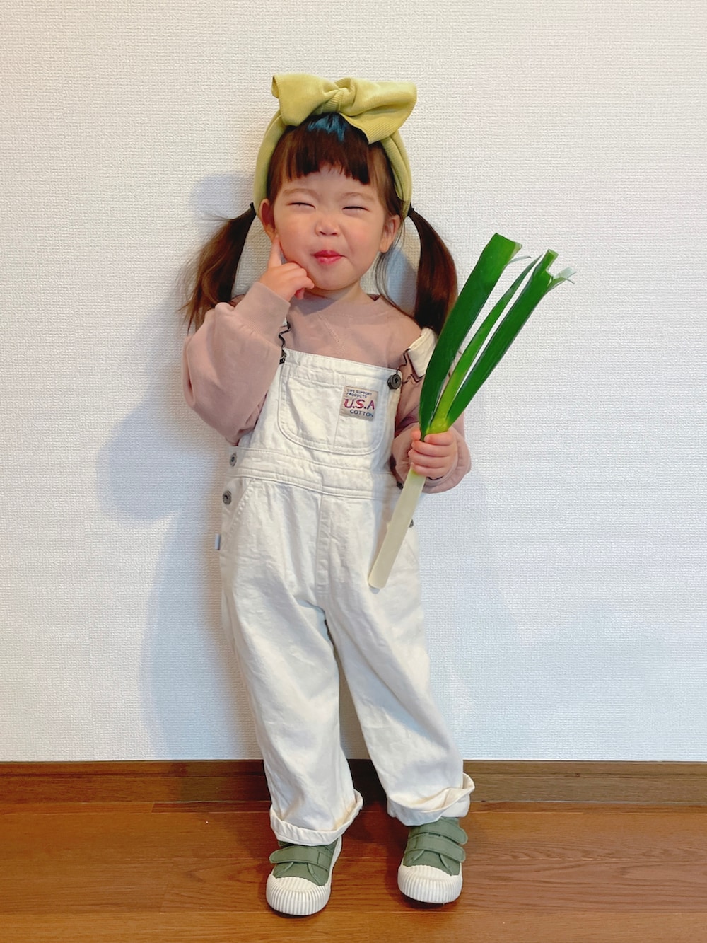 ピンク系のスウェット、ホワイト系のサロペット/オーバーオール、グリーン系のスニーカーを着用したキッズの冬コーディネートの2枚目の写真