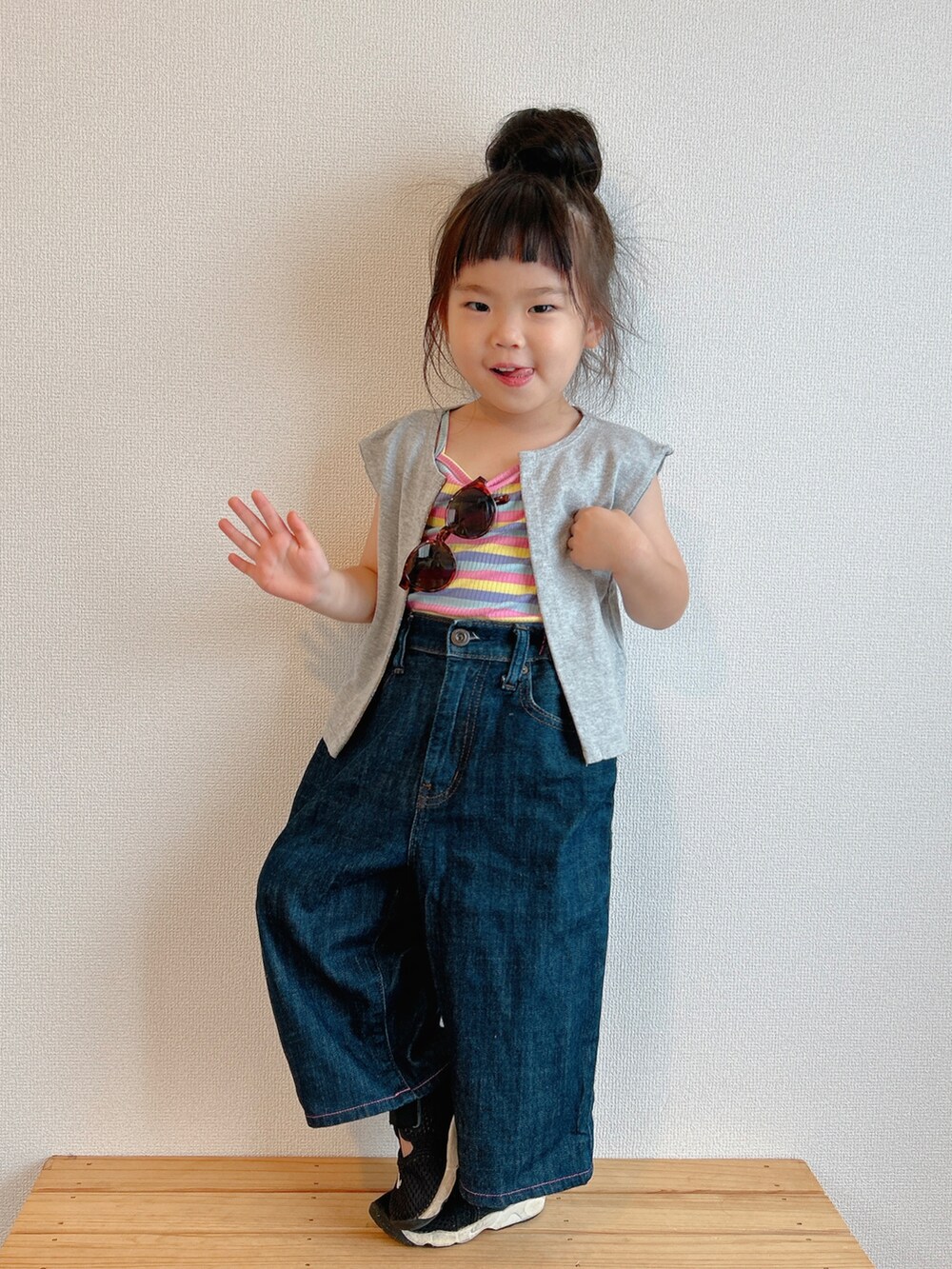 イエロー系のキャミソール、グレー系のベスト、ブルー系のデニムパンツを着用したキッズの夏コーディネートの3枚目の写真