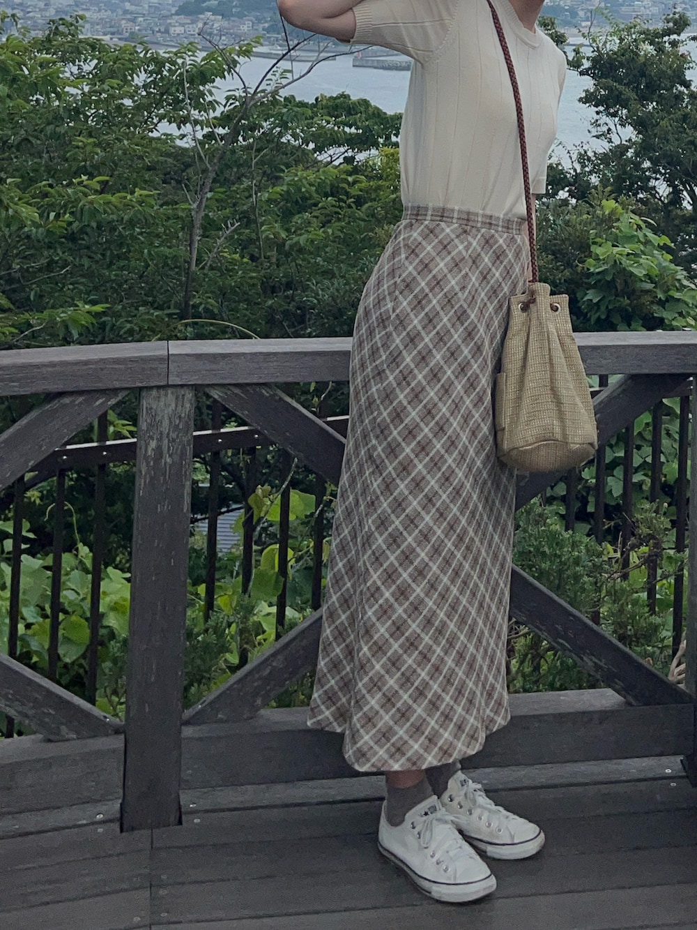 ホワイト系のスニーカー、ベージュ系のニット/セーター、ベージュ系のかごバッグを着用したレディースの秋コーディネートの2枚目の写真