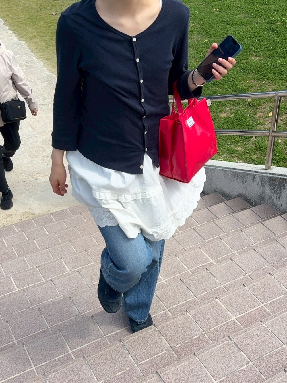 ブルー系のスニーカー、レッド系のハンドバッグを着用したレディースの春コーディネートの4枚目の写真