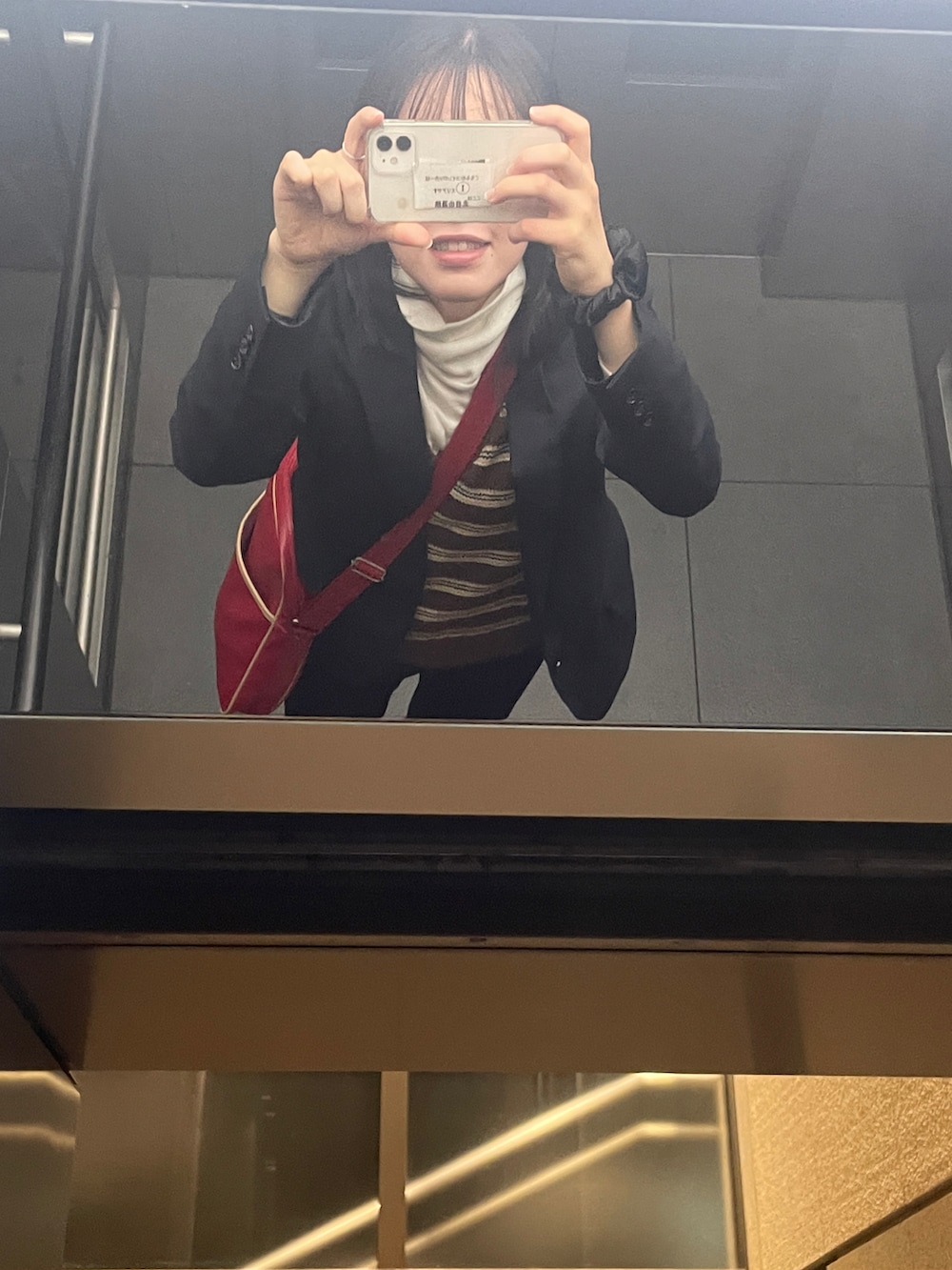 ブラック系のテーラードジャケット、レッド系のショルダーバッグを着用したレディースの秋コーディネートの2枚目の写真