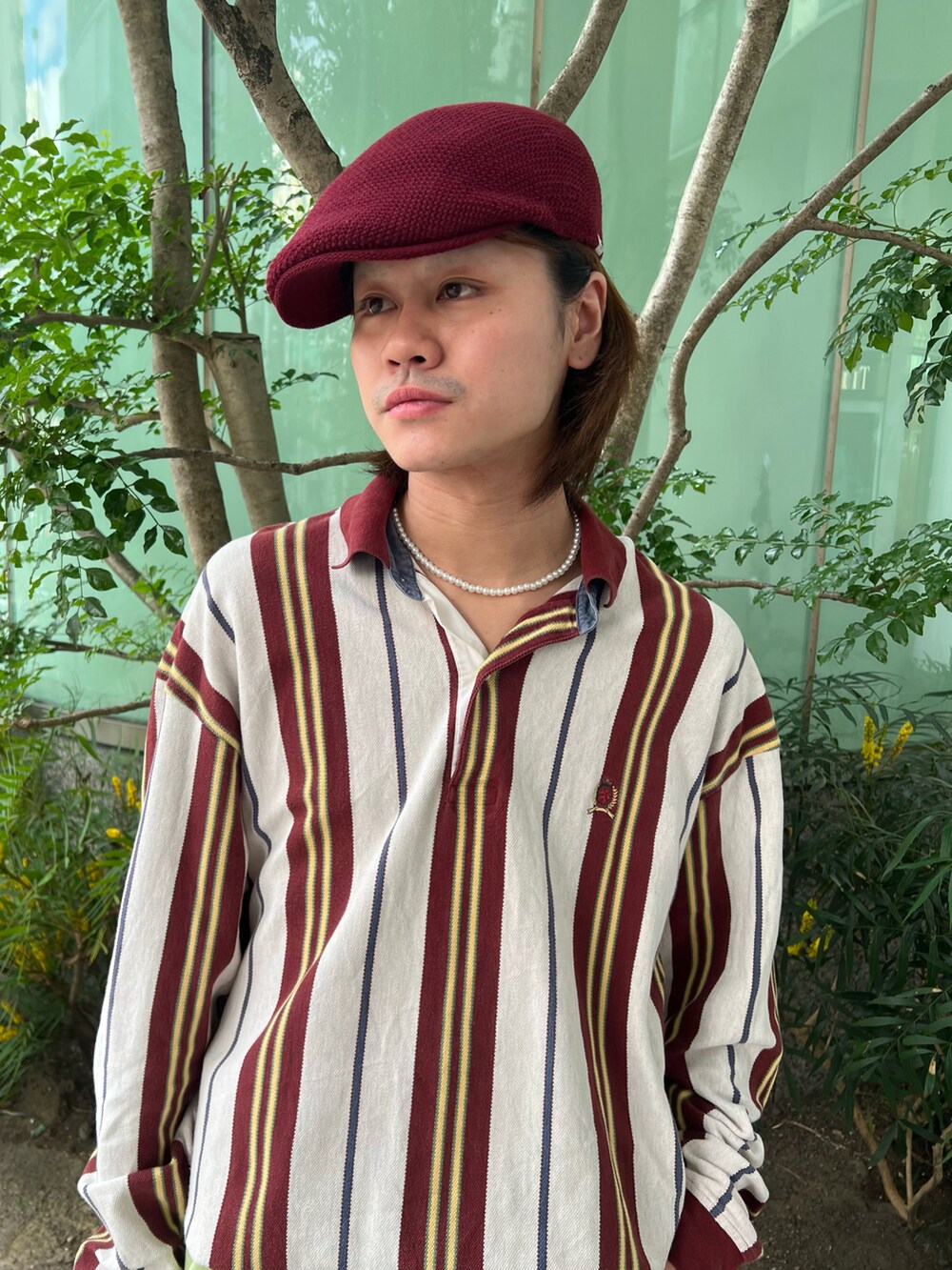 レッド系のトップス、グリーン系のパンツ、レッド系のハンチング/ベレー帽を着用したメンズの秋コーディネートの3枚目の写真