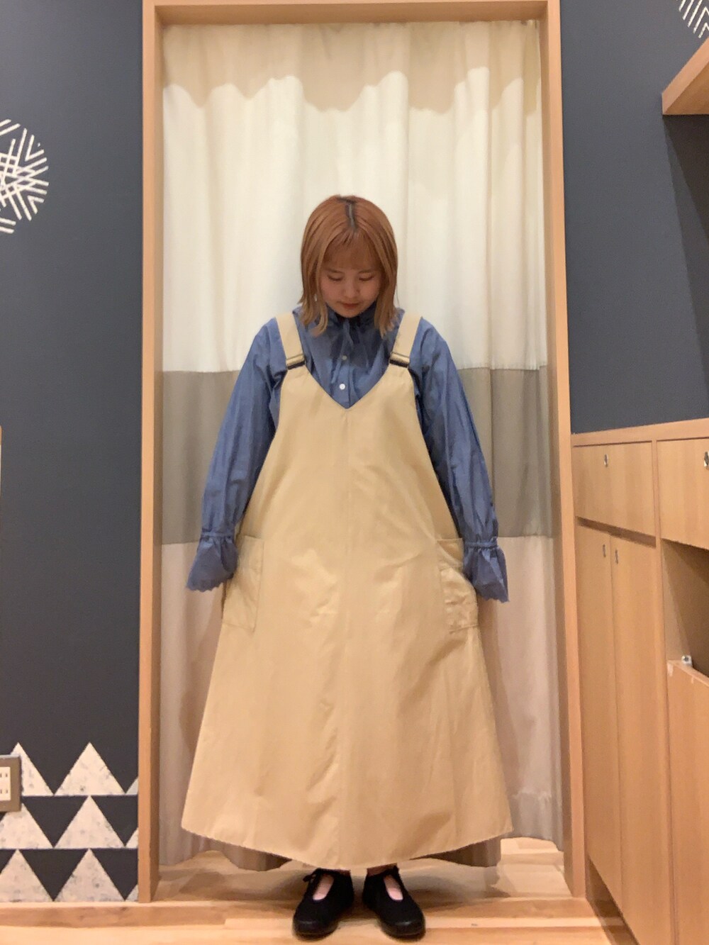 ブラック系のスニーカー、ベージュ系のワンピース、ブルー系のシャツ/ブラウスを着用したレディースの春コーディネートの2枚目の写真