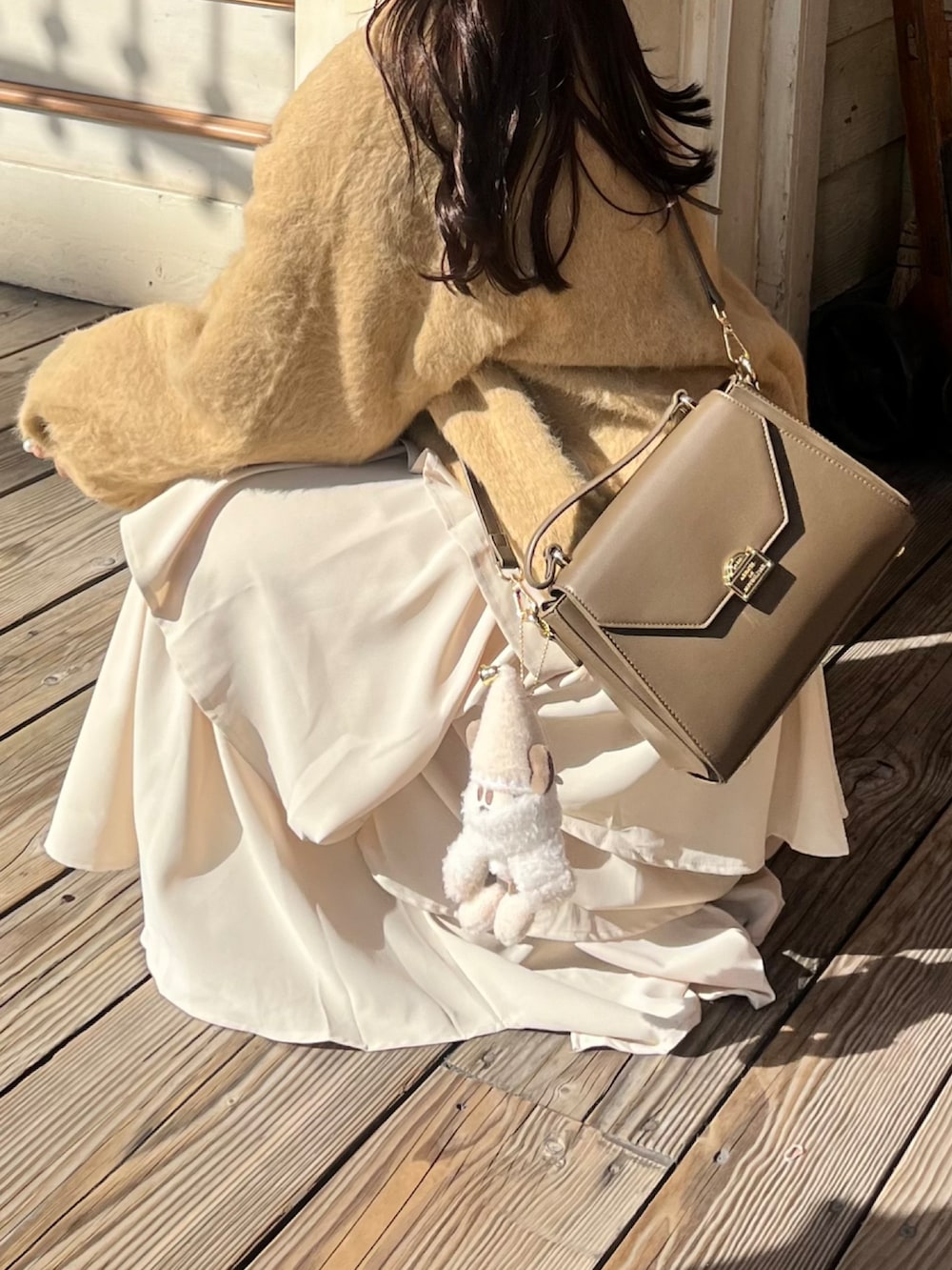 ベージュ系のトップス、ブラウン系のバッグ、ホワイト系のスカートを着用したレディースの秋コーディネートの3枚目の写真