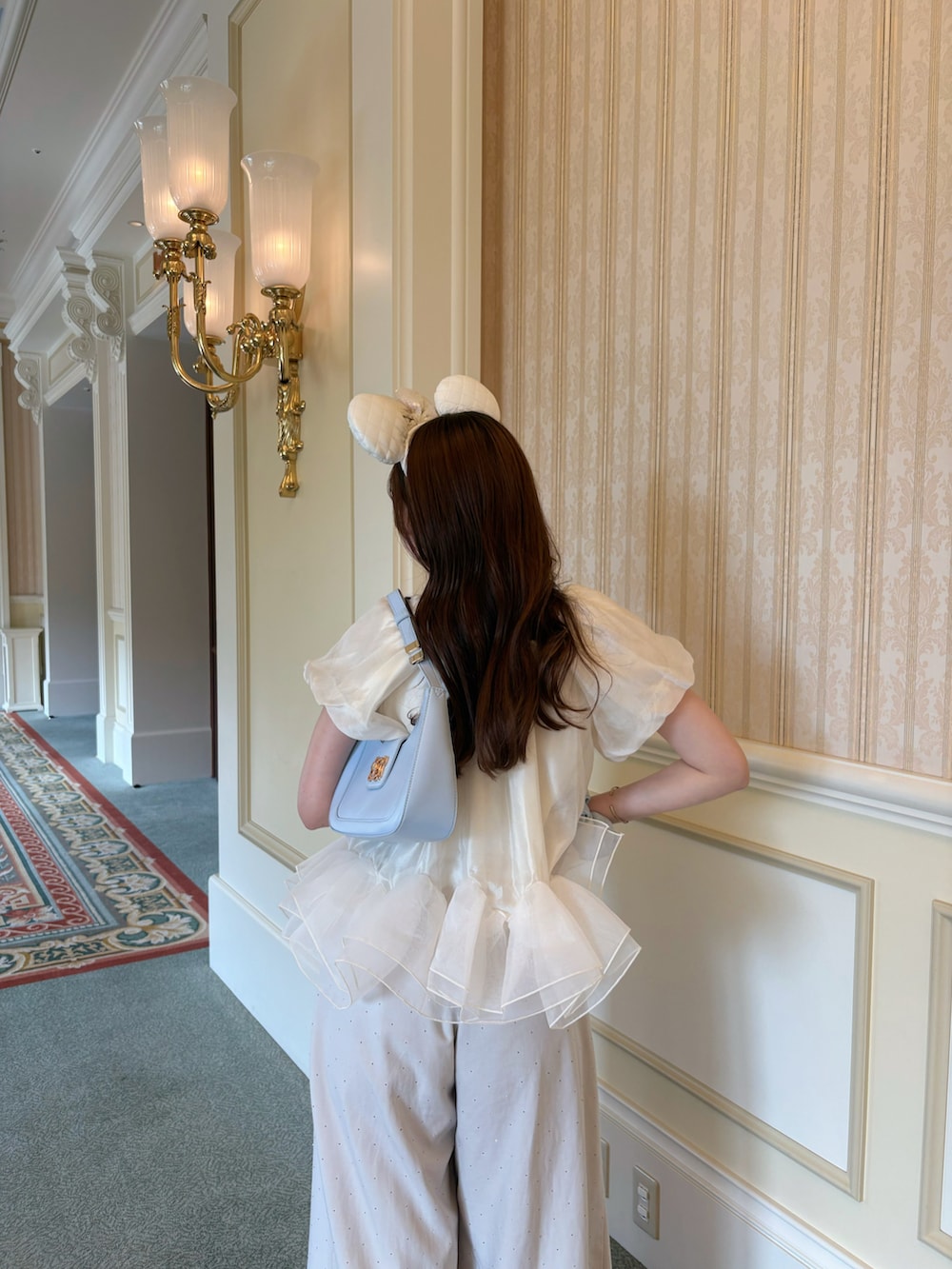 ベージュ系のその他パンツ、ブルー系のハンドバッグ、ホワイト系のパンプスを着用したレディースの夏コーディネートの3枚目の写真