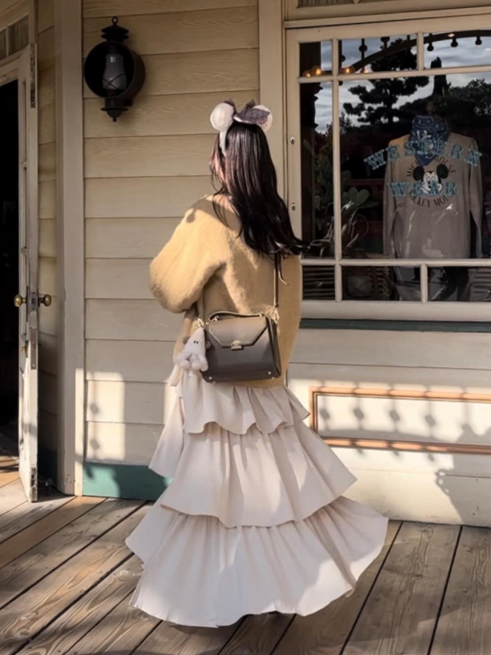 ベージュ系のトップス、ブラウン系のバッグ、ホワイト系のスカートを着用したレディースの秋コーディネートの2枚目の写真